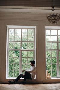 Man sitting on window sill at home
