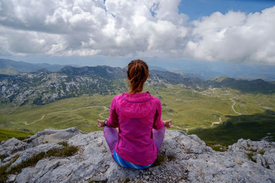 Rear view of woman looking at mountains against sky