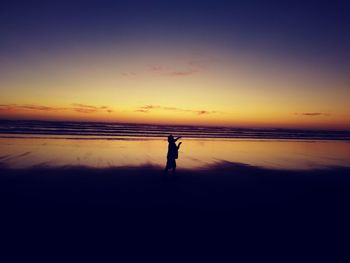 Silhouette man standing on beach against clear sky during sunset