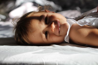 Portrait of little girl lying on bed