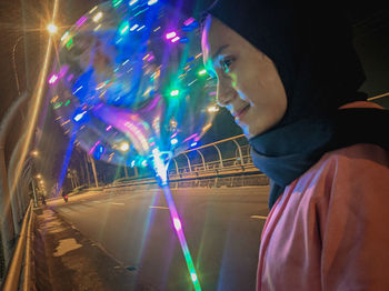 Portrait of boy looking at illuminated city at night