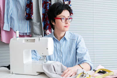 Craftswoman sitting by sewing machine on table at workshop