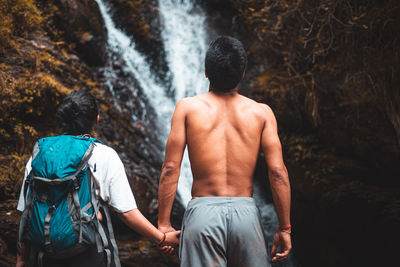 Rear view of man in waterfall at forest