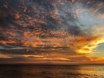 Scenic view of sea against dramatic sky during sunset