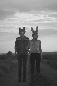 Friends standing on field against sky