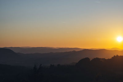 Scenic view of silhouette mountains against orange sky