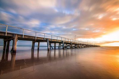 Pier on sea against cloudy sky