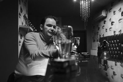 Man smoking cigarette while having drink at table in bar