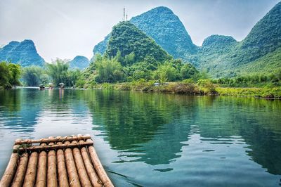 Wooden raft in lake against green mountains