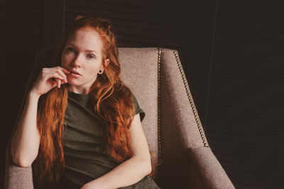 Portrait of young woman sitting on armchair at home