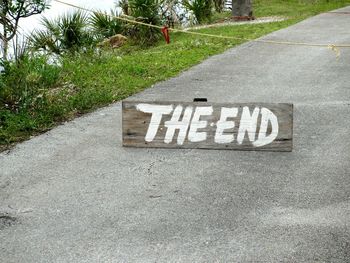 The end text on wooden signboard on road