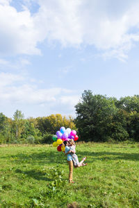 Woman with umbrella on field against sky