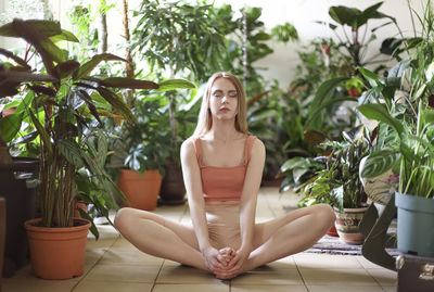 Woman exercising amidst plants at home