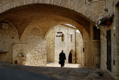 Rear view of priest walking on footpath amidst buildings in town