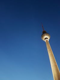 Low angle view of communications tower against blue sky