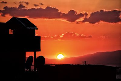 Silhouette buildings against orange sky