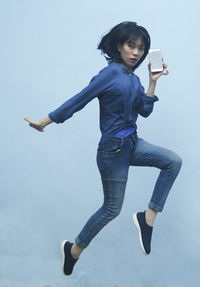 Portrait of young woman jumping against white background