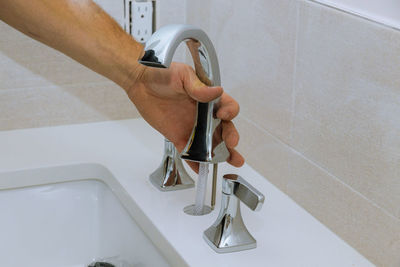 Cropped hand of man repairing faucet at sink