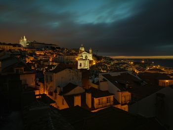 View of town against cloudy sky at night