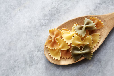 Close-up of farfalle in wooden spoon on marble