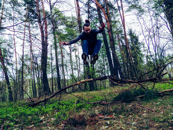 Low angle view of man with arms outstretched in forest