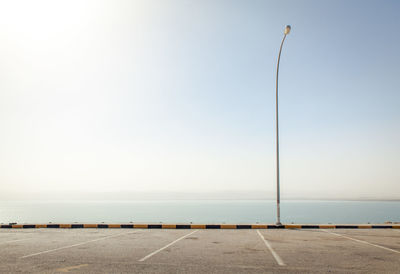 Street light by sea against sky