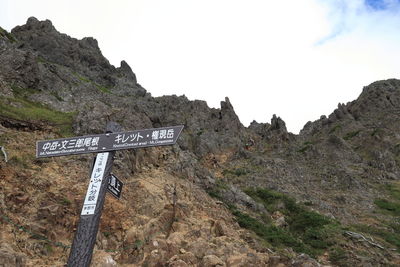 Road sign on mountain against sky