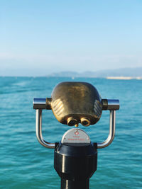 Close-up of coin-operated binoculars against sea