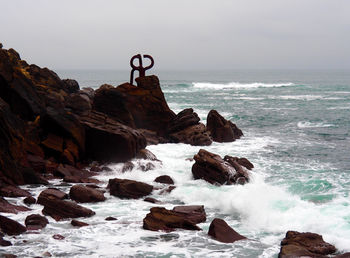 Scenic view of rocks in sea against sky