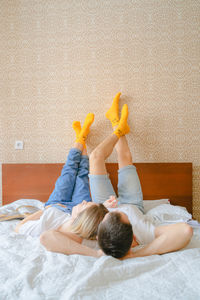 Rear view of woman sitting on bed at home
