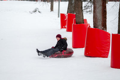 Winter activity. tubing. a teenage boy rolls on a red tubing on a specially equipped safe
