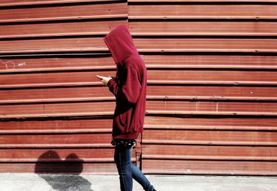 Side view of man standing against brick wall