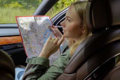 Portrait of young woman using mobile phone while sitting in car