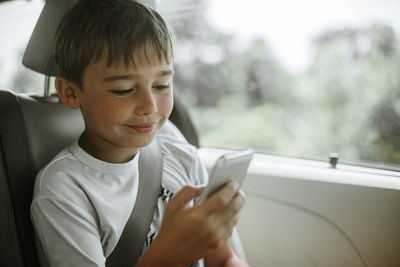 Side view of boy looking through mobile phone