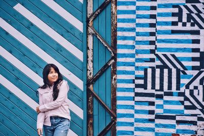 Young woman standing against wall