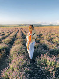 Rear view of woman standing on field against sky