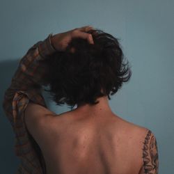 Rear view of shirtless woman against gray background