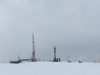 Electricity pylon on snow covered field against sky