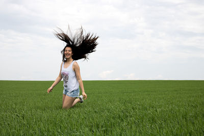 Woman jumping on field against sky