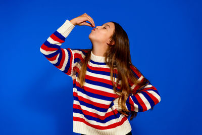 Low angle view of young woman standing against blue background