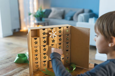 Happy excited little boy opens christmas advent calendar surprise box with gingerbread and sweets.