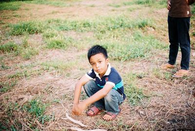 Portrait of boy crouching on field