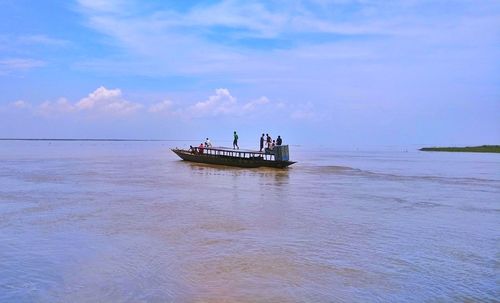 People in boat on sea against sky