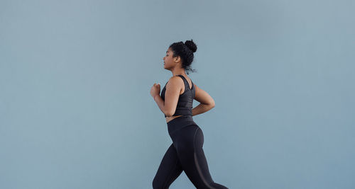 Side view of woman standing against blue background