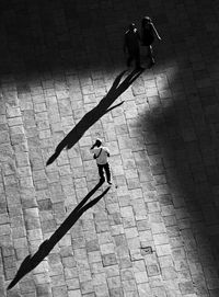 High angle view of people walking with shadow on footpath