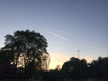 Low angle view of vapor trails in sky at sunset