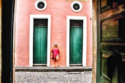 Woman standing by window of building