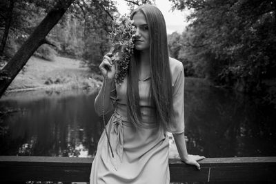 Young woman standing against pond