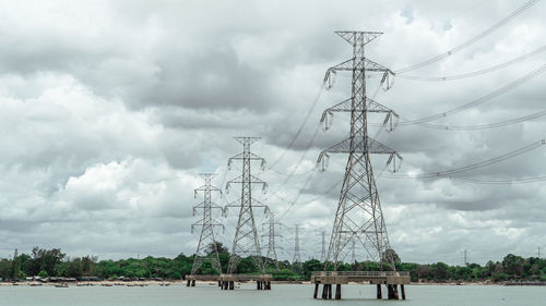 Electricity pylon on field against sky