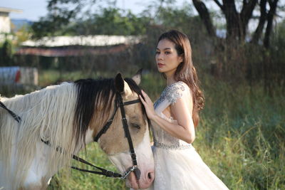 Portrait of young woman with horse standing on field